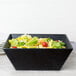 An American Metalcraft black square melamine bowl filled with salad.