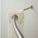 A Crescent Suite stainless steel curved shower curtain rod with white curtains hanging from it.
