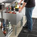 A man standing at an underbar counter with a drink.