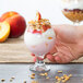 A person holding a Libbey Belgian beer tasting glass of yogurt with granola and fruit.