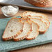Sliced bread on a cutting board with a bowl of ADM High Gluten Flour.
