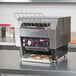 A Hatco TQ-400 conveyor toaster with bread on it sitting on a counter.
