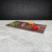 An Elite Global Solutions faux walnut melamine rectangular serving board with various vegetables on it.