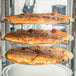 A pizza on a rack in a Hatco Flav-R-Fresh Humidified Pizza Display Cabinet.