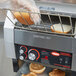 A person holding a bag of bread and putting a slice into a Hatco conveyor toaster.