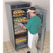A man putting trays of food into a Hatco Flav-R-Savor holding and proofing cabinet.