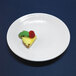 A white Elite Global Solutions round melamine plate with a piece of pineapple with a raspberry on it.