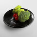 A black Elite Global Solutions Pebble Creek round plate with broccoli and tomatoes on it.