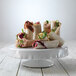 A white Elite Global Solution ruffled edge melamine cake stand with food on it.