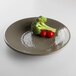 A Elite Global Solutions round melamine plate in mushroom color with broccoli and tomatoes on it.