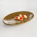 An Elite Global Solutions Pebble Creek Tapenade-colored melamine oval platter with a piece of bread, cheese, and a tomato.