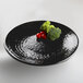 An Elite Global Solutions black melamine plate with broccoli and tomatoes on it.