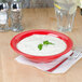 A Thunder Group Pure Red melamine bowl filled with white sauce and a leafy green sprig.