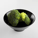 A black Elite Global Solutions melamine bowl filled with broccoli on a white surface.