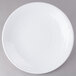 A close-up of an Elite Global Solutions white plate with a white rim on a gray surface.