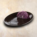 An Elite Global Solutions aubergine-colored oval platter with a piece of red cabbage on it.