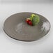 An Elite Global Solutions Pebble Creek mushroom-colored melamine plate with broccoli and cherry tomatoes on it.