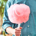 A man holding a pink Great Western cotton candy on a white stick.