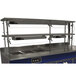 An Advance Tabco double tier self service food shield with stainless steel shelves on a stainless steel counter.
