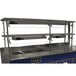 An Advance Tabco double tier self service food shield with stainless steel shelves on a blue counter.