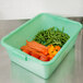 A Vollrath Traex green perforated drain box filled with vegetables.