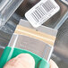 A person holding a Unger stainless steel razor blade with a green and white label.