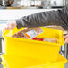 A person holding a Vollrath yellow perforated drain box filled with food.