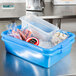 A blue Vollrath Traex food storage container with ice and food in it.