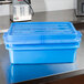 A Vollrath blue plastic food storage container with a lid on a counter.
