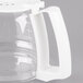A clear glass coffee pot with a white handle.