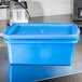 A Vollrath Traex blue polypropylene food storage container with a lid on a counter.