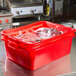 A red Vollrath Traex container with meat in it.