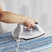 A person using a Proctor Silex hospitality iron to iron clothes on an ironing board.