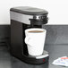 A Hamilton Beach single serving pod coffee maker with a white cup of coffee.