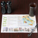 A Hoffmaster Italia paper placemat with a map of Italy on a table with a glass of liquid and a fork.