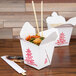 Two white Fold-Pak Chinese take-out containers on a table.