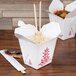 A Fold-Pak Pagoda Chinese take-out container filled with food and chopsticks.