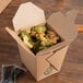 A Fold-Pak Earth Chinese take-out container on a table filled with broccoli and chicken.