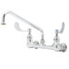 A white T&S wall mount pantry faucet with 4" wrist action handles and a 12" swing nozzle.