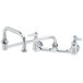 A T&S chrome wall mount faucet with 2 handles and a double joint nozzle.