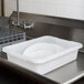 A white plastic Rubbermaid bus tub on a stainless steel counter.