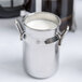An American Metalcraft metal milk can creamer filled with white liquid.