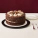 A D&W Fine Pack cake container holding a chocolate cake with white frosting and nuts on top.