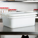A Tablecraft white plastic container with lid on a counter.