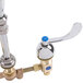 A chrome T&S deck mount faucet with white double valve pedals and serrated nozzle.