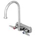 A chrome T&S wall mount faucet with a gooseneck spout and two handles, one blue.