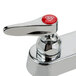 A close-up of a T&S chrome deck-mount workboard faucet with red accents.