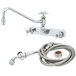 A T&S chrome wall mount faucet with hose and angled spray valve.