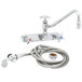 A chrome T&S wall mount workboard faucet with hose and angled spray valve.