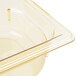 A Vollrath 1/6 size amber plastic food pan on a counter.